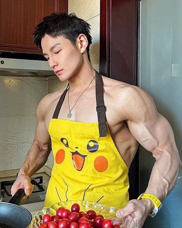 Hình ảnh hot boy đẹp trai có một người đàn ông mặc chiếc tạp dề màu vàng chuẩn bị thức ăn trong bếp