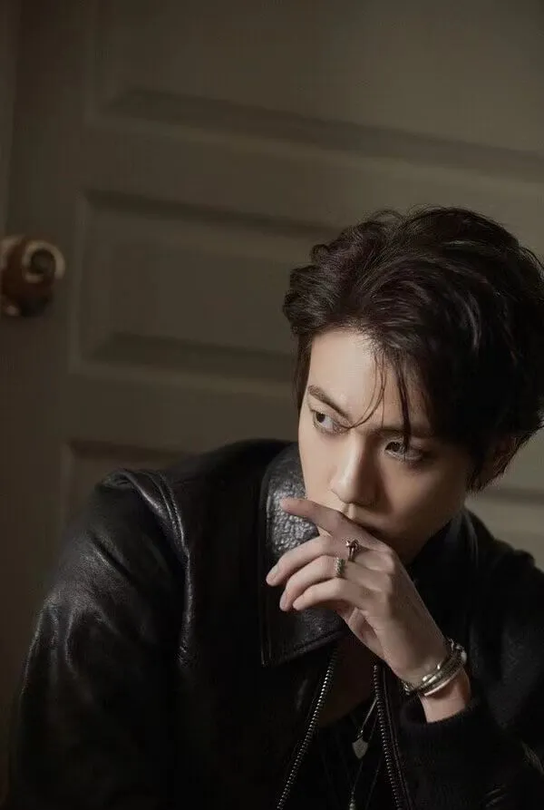 Jin ảnh bts khóc có một người đàn ông mặc áo khoác da màu đen ăn bánh rán