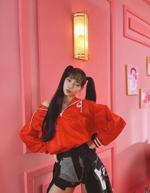 Ảnh lisa blackpink có một người phụ nữ đứng trước bức tường màu hồng mặc áo khoác đỏ và quần short đen