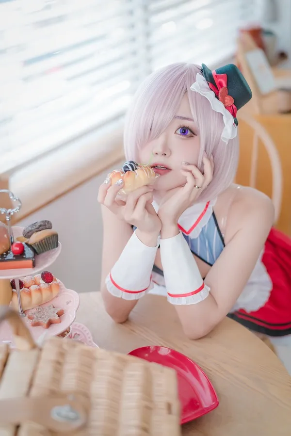 Ảnh mash kyrielight cosplay cô gái có mái tóc màu hồng ăn bánh rán khi ngồi bàn
