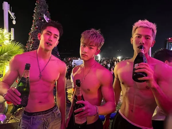 Ảnh trai đẹp múi ba người đàn ông không mặc áo đứng cạnh nhau cầm chai bia