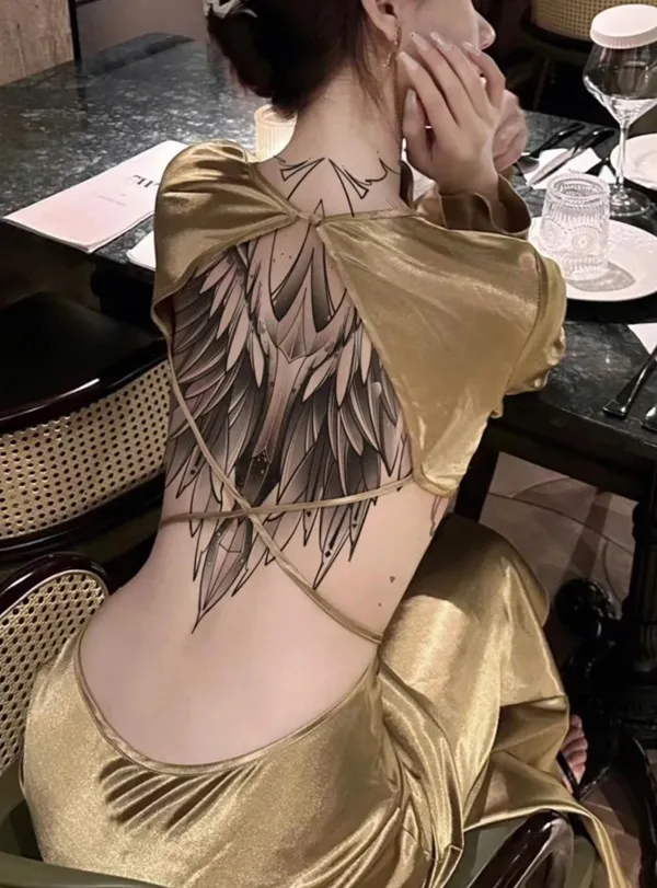 Có một người phụ nữ ngồi bàn với hình xăm trên lưng