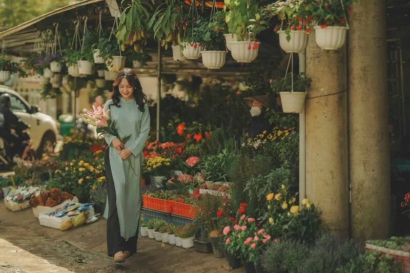 Chụp ảnh tết có một người phụ nữ đang đứng trước cửa hàng hoa