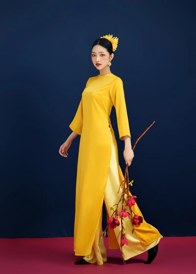 Hoa chụp ảnh tết người phụ nữ đang mặc một chiếc váy dài màu vàng và cầm
