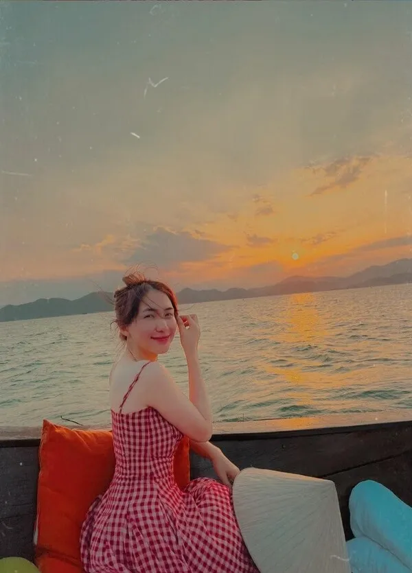 Ảnh hoà minzy có một người phụ nữ đang ngồi trên chiếc ghế dài bên mặt nước