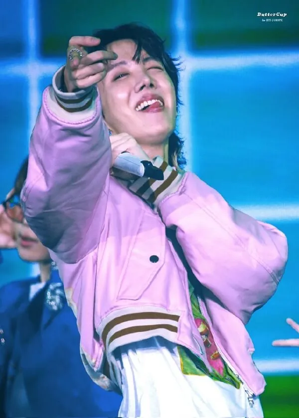 J-hope ảnh dìm có một người đàn ông mặc áo khoác màu hồng và cà vạt cầm micro