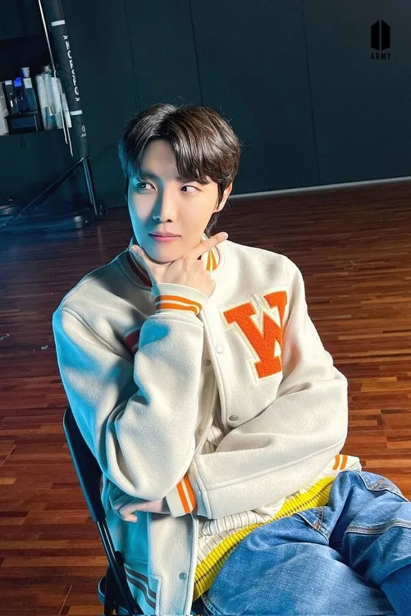 J-hope ảnh dìm có một chàng trai trẻ ngồi trên ghế với cằm