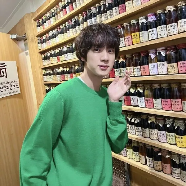 Ảnh jin bts đẹp có một người đàn ông đang đứng trước bức tường của lọ