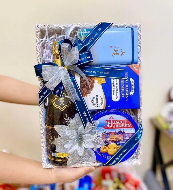 Khay gỗ đựng hoa quả có một người cầm hộp sôcôla và kẹo