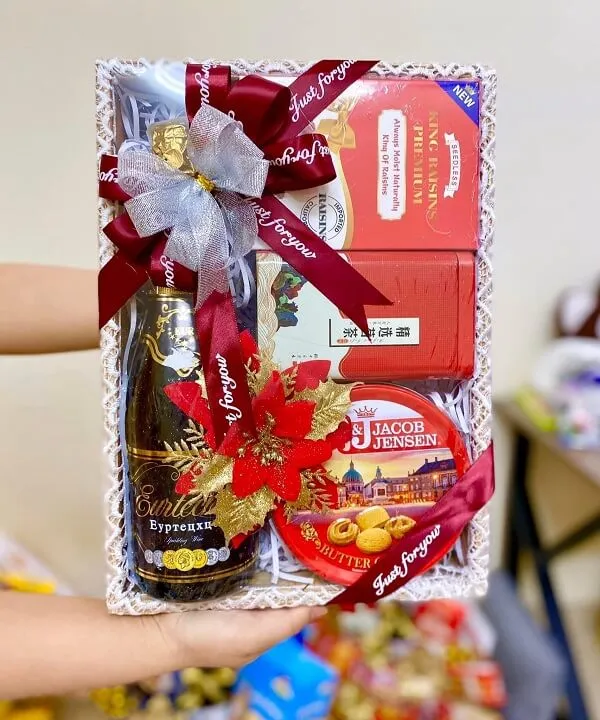 Khay gỗ đựng quà tết có một người cầm hộp sôcôla và chai rượu