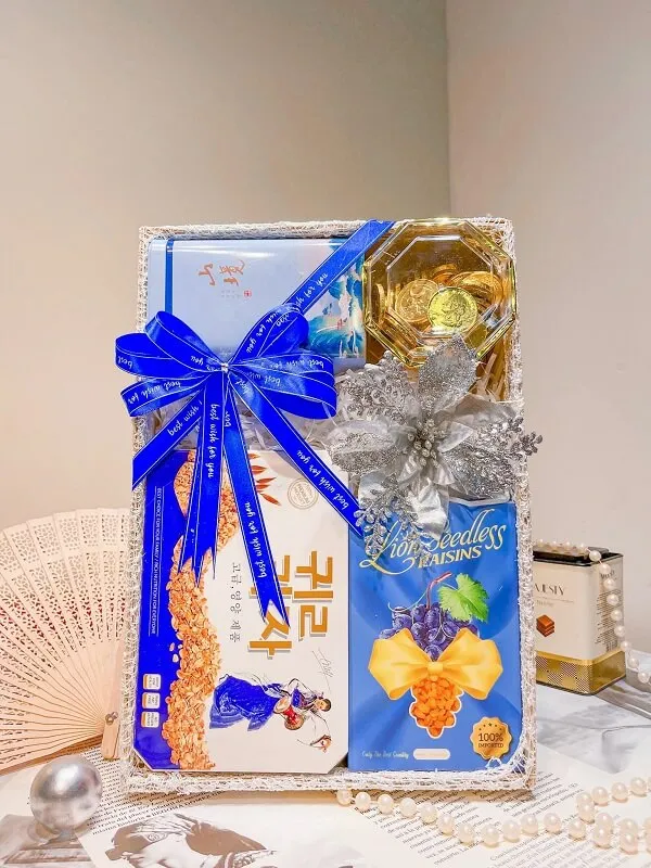Khay gỗ đựng quà tết có một hộp sôcôla và người hâm mộ trên bàn