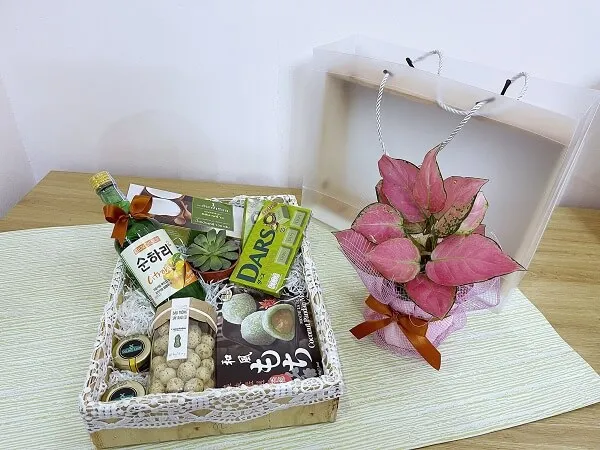 Khay gói quà tết có một hộp sôcôla kẹo và hoa trên bàn