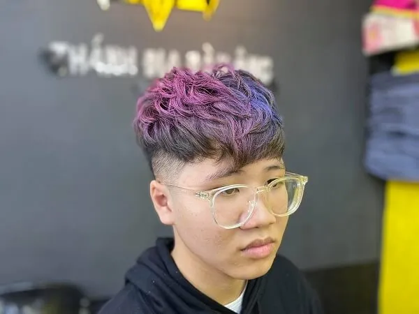 Tóc mohican có một chàng trai trẻ với mái màu tím và kính ngồi bàn