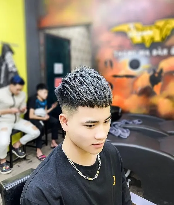 Kiểu tóc mohican ngắn có một chàng trai trẻ ngồi trên ghế dây chuyền quanh cổ
