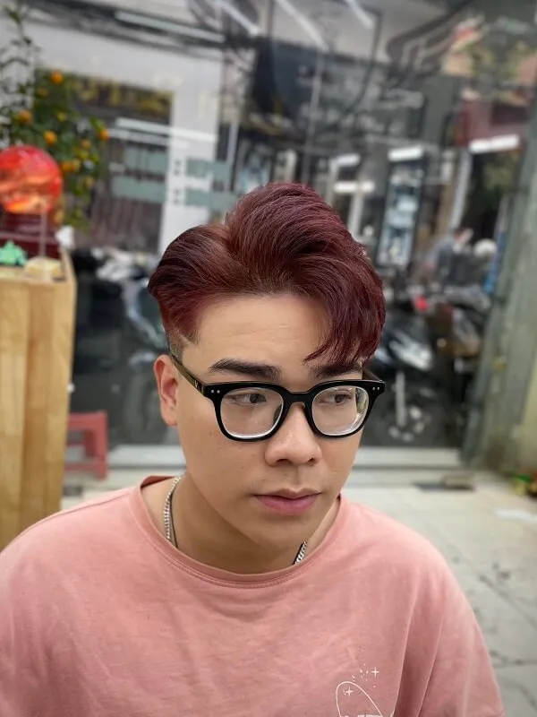 Kiểu tóc nam side part có một người đàn ông với mái đỏ đeo kính và áo sơ mi màu hồng