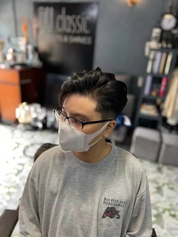 Tóc nam side part có một chàng trai trẻ đeo mặt nạ trong cửa hàng cắt