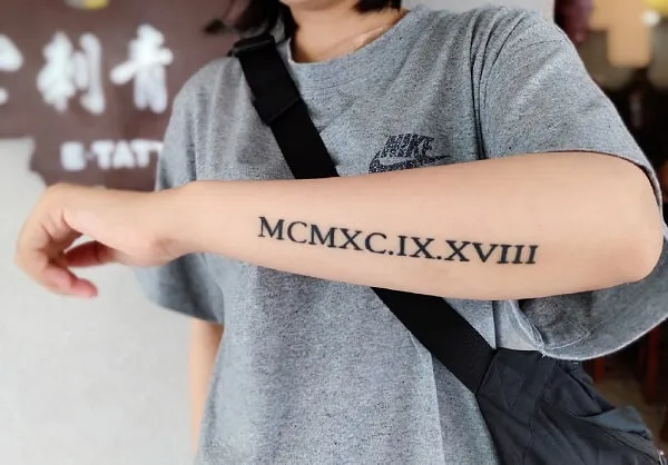 Có một người phụ nữ hình xăm chữ số la mã trên cánh tay của cô ấy