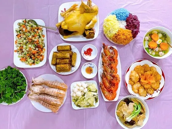 Có rất nhiều đĩa thức ăn ngồi trên bàn với một tấm vải màu hồng