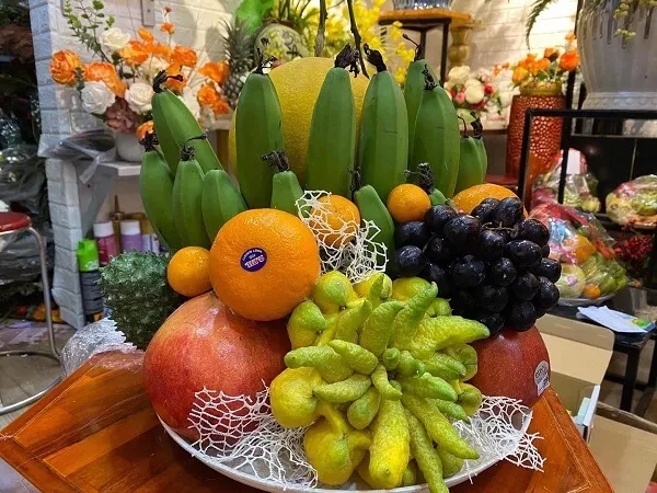 Mâm ngũ quả ngày tết táo cam nho và chuối được sắp xếp trong một cái bát trên bàn