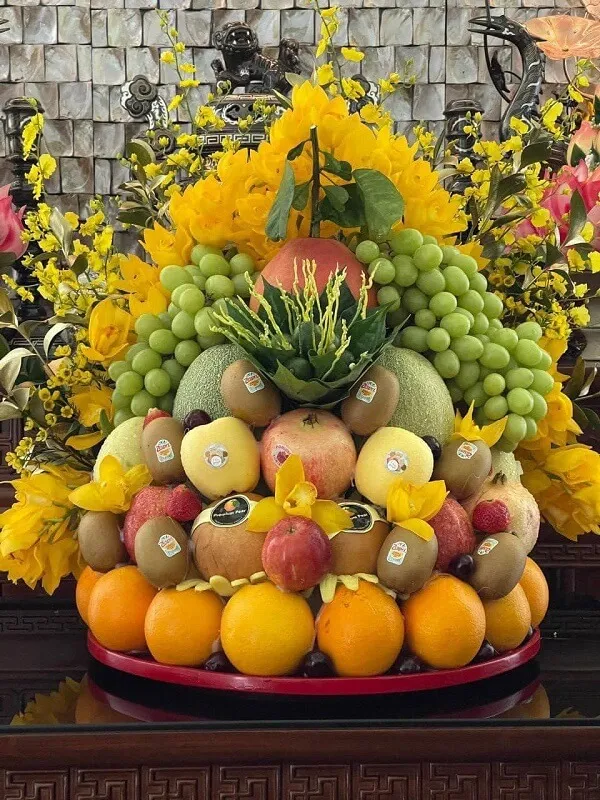 Mâm ngũ quả trung thu có một sự sắp xếp lớn của trái cây và hoa trên bàn