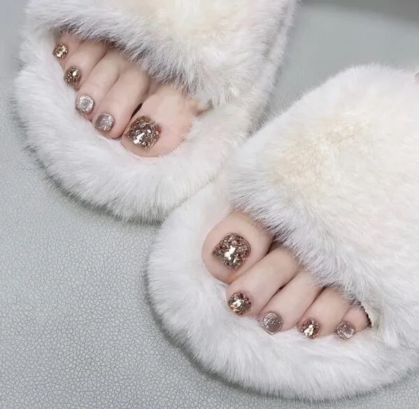 Mẫu nail chân đẹp có một đôi dép lông màu trắng với rhines trên chúng