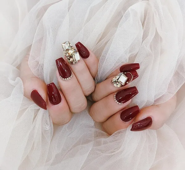 Nail cô dâu sang chảnh cận cảnh bàn tay của một người phụ nữ với móng màu đỏ và vàng