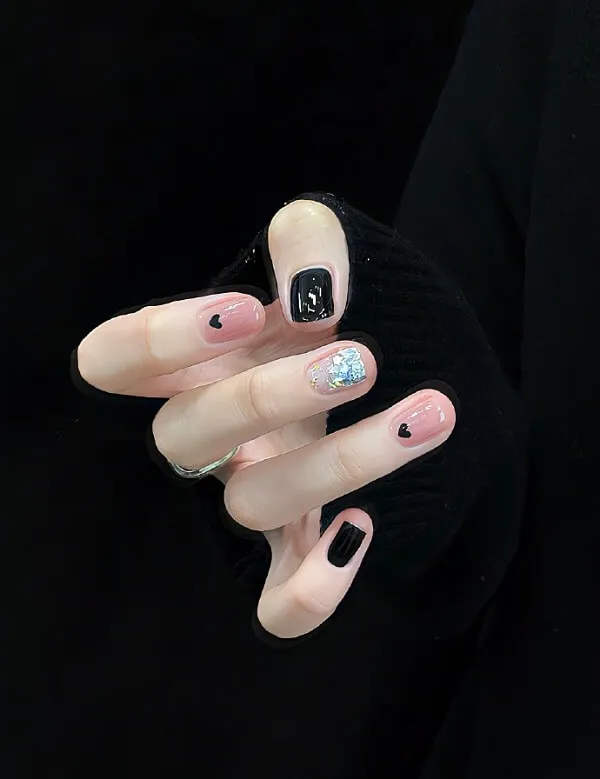 Mẫu nail chân đẹp có một bàn tay của người phụ nữ với móng màu đen và trắng cầm hồng