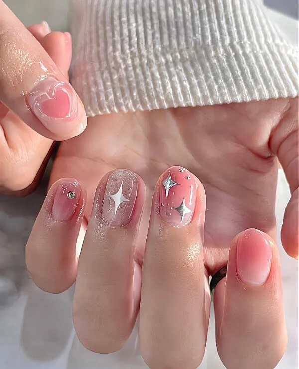 Mẫu nail đẹp có một người phụ nữ cầm móng tay màu hồng và trắng với các ngôi sao trên đó