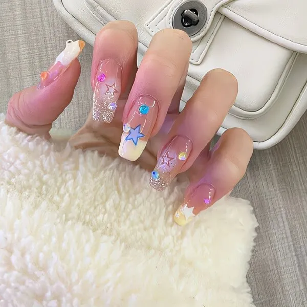 Màu nail đẹp tôn da có một người cầm ví trắng và làm móng tay hồng với những ngôi sao trên đó
