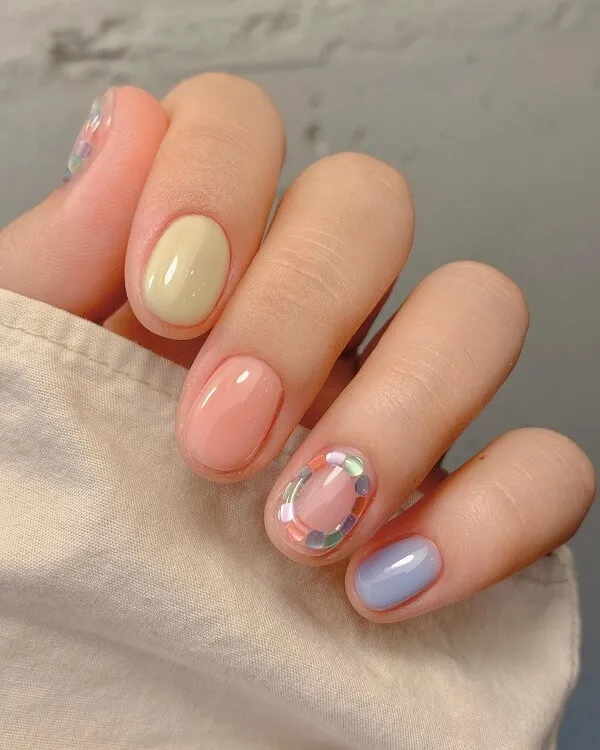 Mẫu nail đơn giản có một bàn tay của người phụ nữ cầm móng màu hồng và xanh với những bông hoa trên đó
