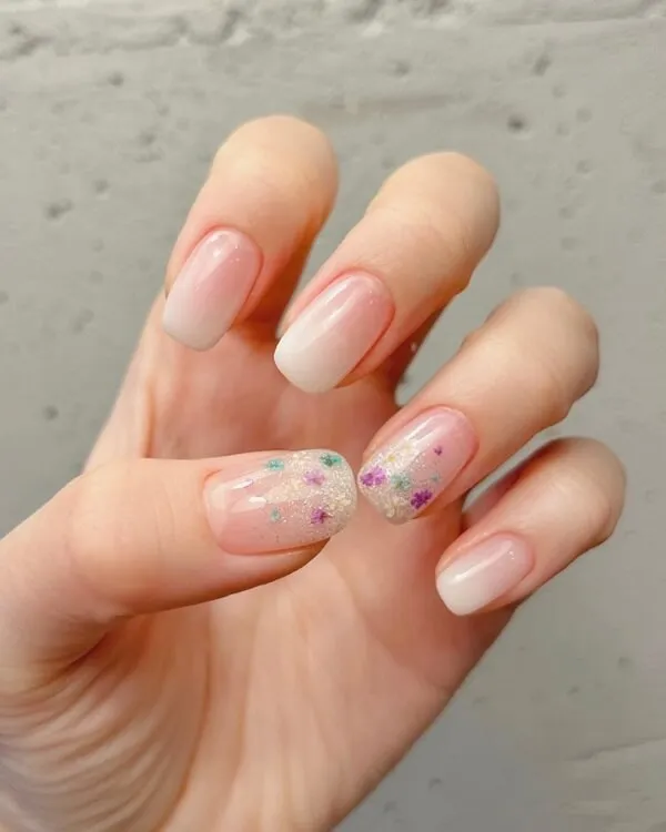 Mẫu nail đơn giản có một người cầm móng tay màu hồng và trắng với confetti trên đó