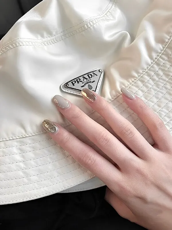 Mẫu nail đẹp đơn giản người phụ nữ đang đội một chiếc mũ trắng với logo hình tam giác trên đó