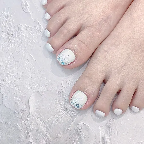 Mẫu nail trắng có đôi chân của một người phụ nữ với các thiết kế màu và xanh trên chúng