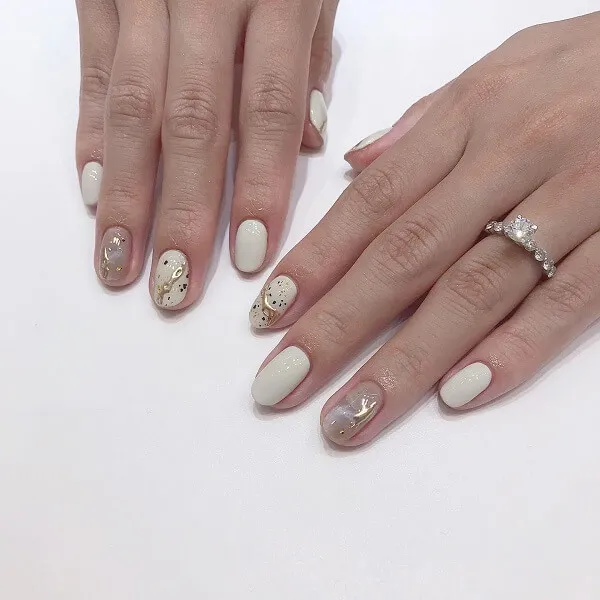 Mẫu nail trắng có một bàn tay của người phụ nữ với móng màu và vàng trên chúng