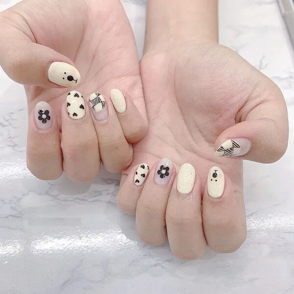 Mẫu nail trắng có một người cầm đôi tay với các thiết kế màu và đen trên chúng