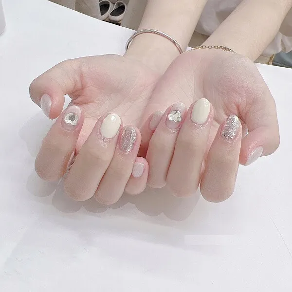 Mẫu nail trắng đây là hình ảnh bàn tay của một người phụ nữ với móng màu và bạc