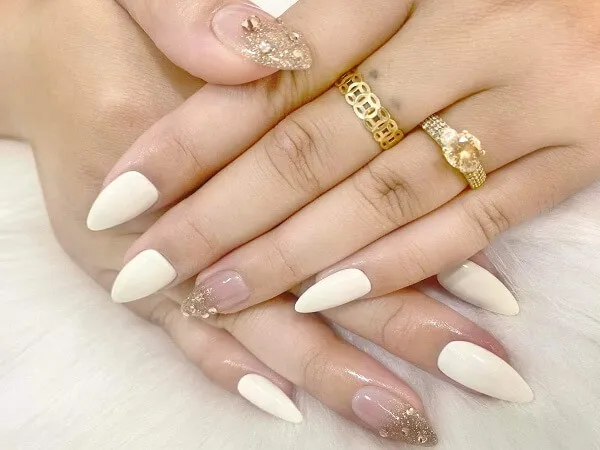 Mẫu nail trắng có một bàn tay của người với móng màu và vàng