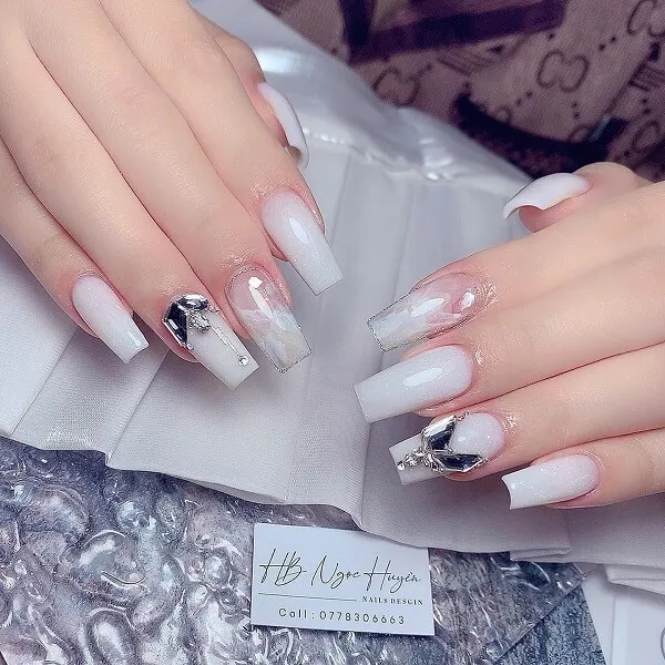 Nail chân màu trắng sữa đây là một bàn tay của người phụ nữ với móng và bạc