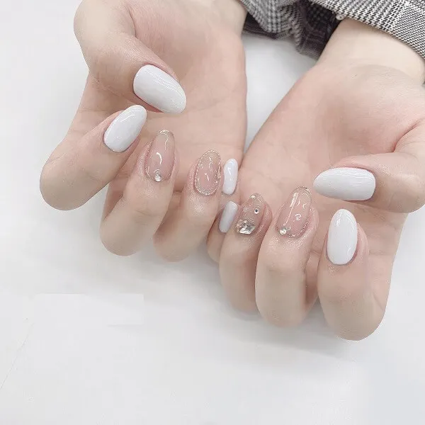 Mẫu nail tráng gương bàn tay được cắt tỉa cẩn thận của một người phụ nữ có móng trắng và làm trong suốt