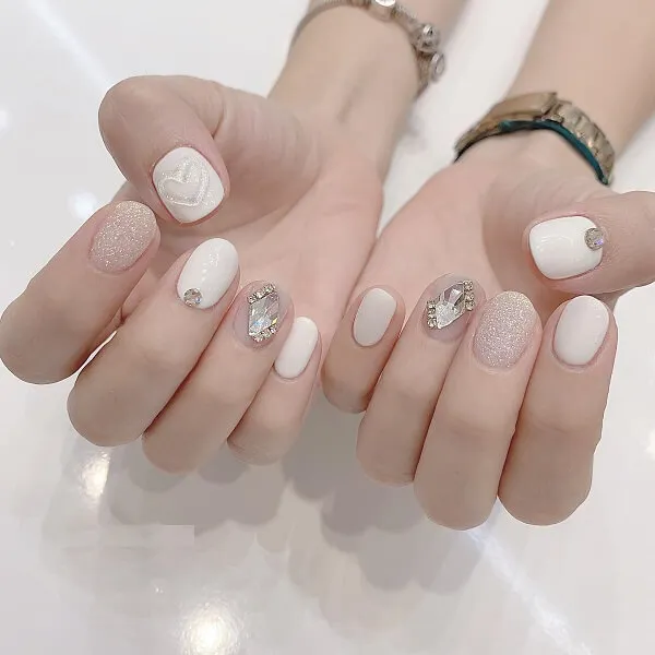 Mẫu nail trắng sang chảnh có hai bàn tay với móng màu và bạc trên chúng