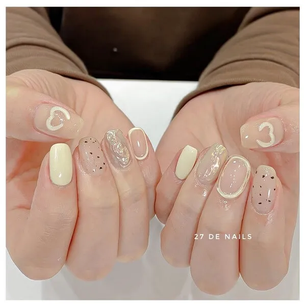Nail chân màu trắng sữa có hai tay cầm một cặp móng giả với thiết kế trên chúng