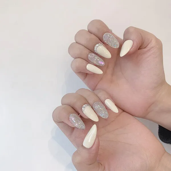Mẫu nail trắng có hai bàn tay với sơn móng và bạc trên chúng