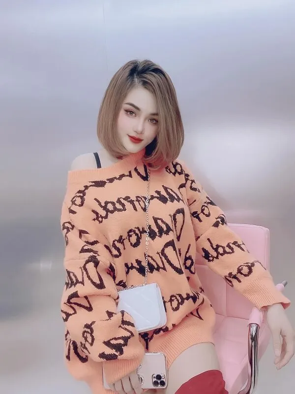 Mẫu tóc bob ngắn có một người phụ nữ ngồi trên ghế màu hồng cầm điện thoại di động