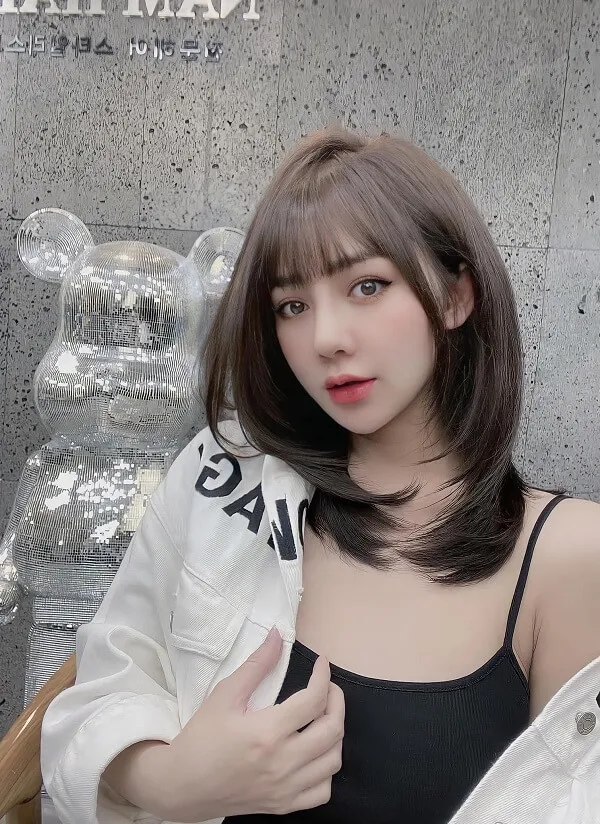 Mẫu tóc bob có một người phụ nữ ngồi trên ghế với chiếc áo khoác trắng
