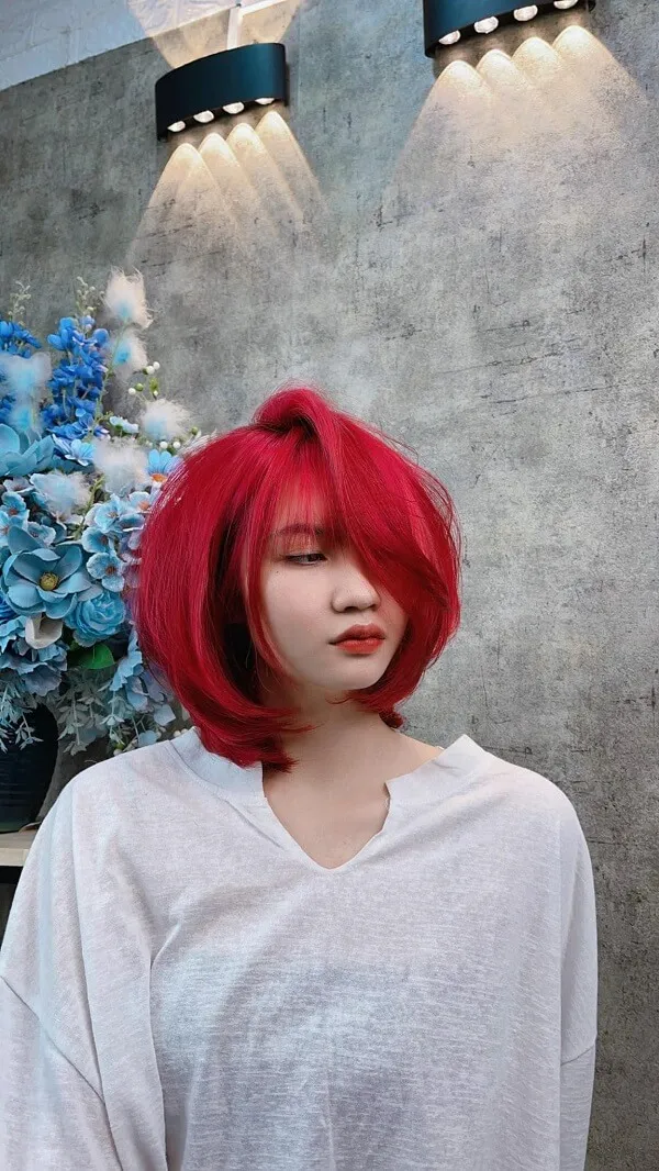 Màu tóc đẹp người phụ nữ vàng với mái đỏ đứng trước bình hoa xanh