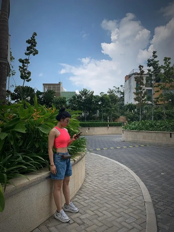 Miu lê sexy có một người phụ nữ dựa vào tường nhìn điện thoại di động của cô ấy