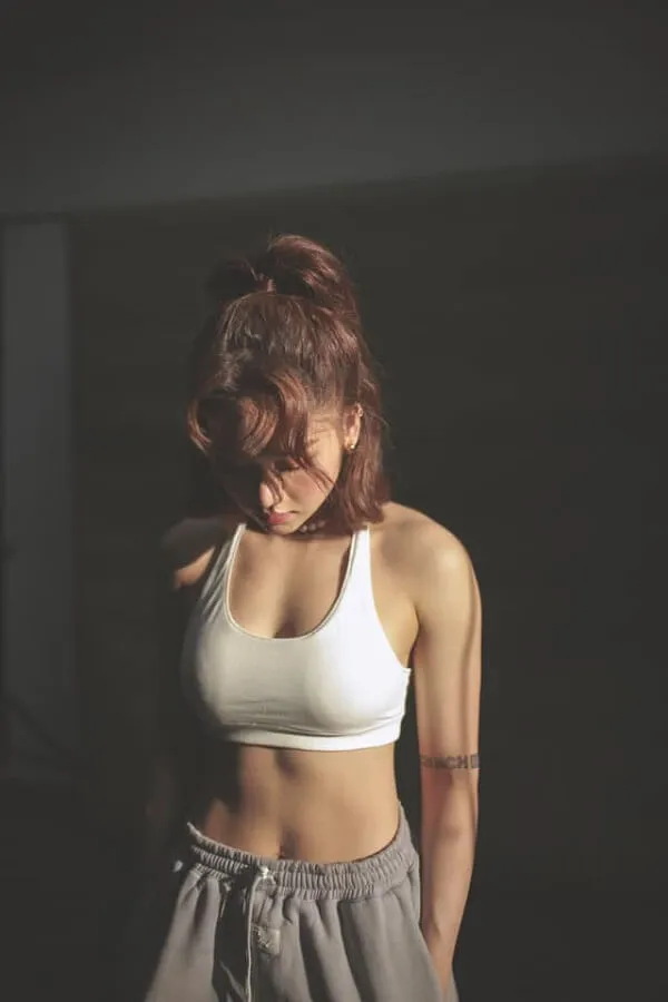 Miu lê sexy có một người phụ nữ mặc áo ngực thể thao màu trắng đứng trong bóng tối