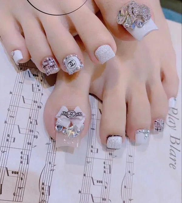 Nail chân có một đôi của người với các thiết kế màu trắng và bạc trên chúng