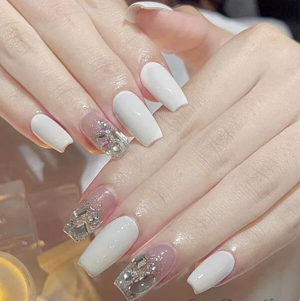 Nail chân màu trắng sữa ai đó đang hoàn thành móng tay của họ với ánh sáng và bạc