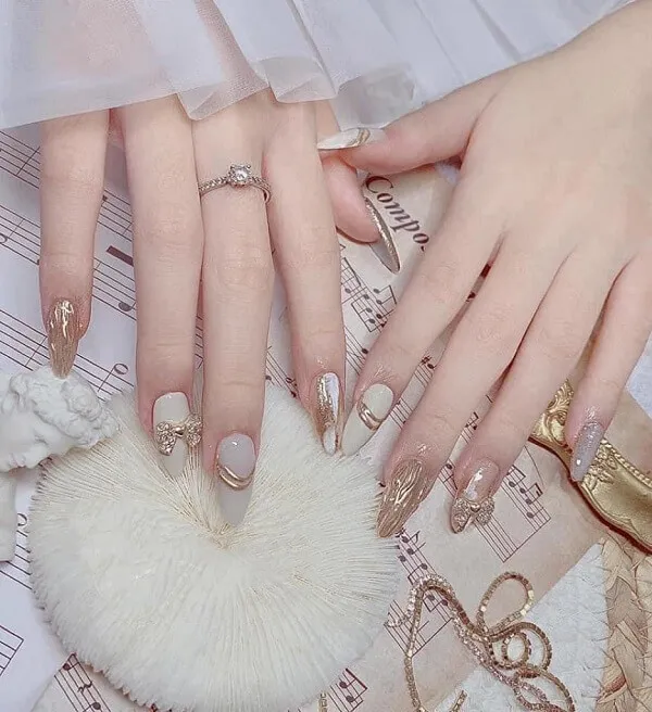 Cưới nail cô dâu màu trắng cận cảnh bàn tay của một người phụ nữ với móng và vàng trên đầu bản nhạc
